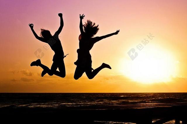 夕阳剪影两个女性开心高兴的跳跃起来背景图片