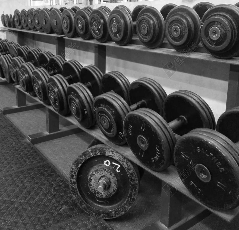 黑色健身整齐架子上整洁排列的杠铃健身锻炼力量背景图片