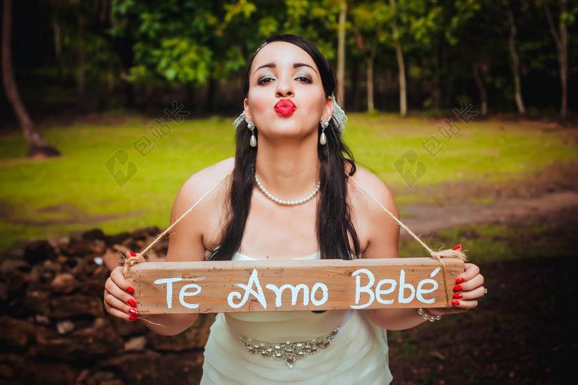 人物美丽野外新娘挂着一个牌子索吻清新户外摄影人物婚礼背景图片