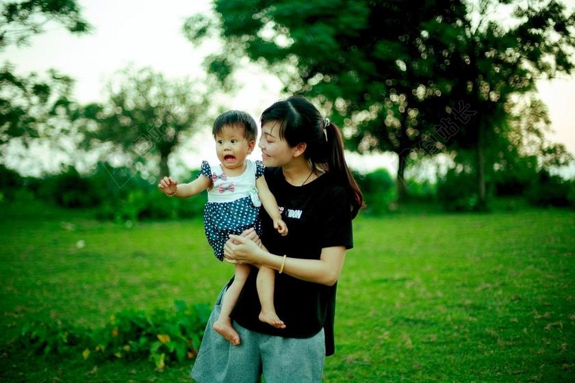 女人抱孩子在草坪上背景图片