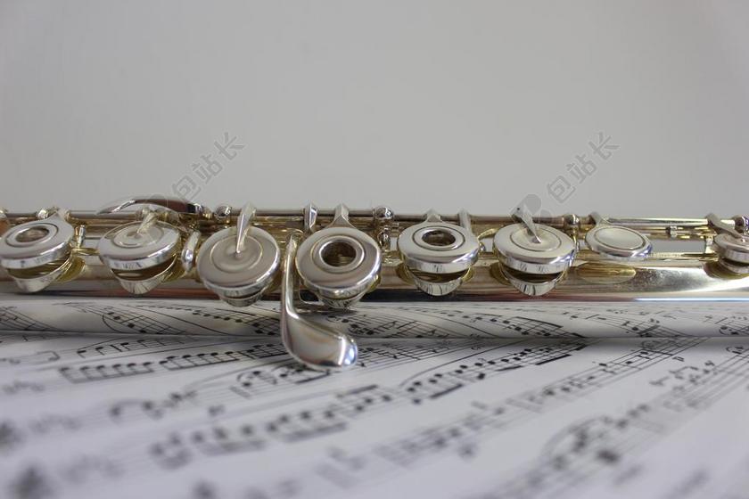 银白音乐文艺清新笛子放在乐谱上宣传背景图片