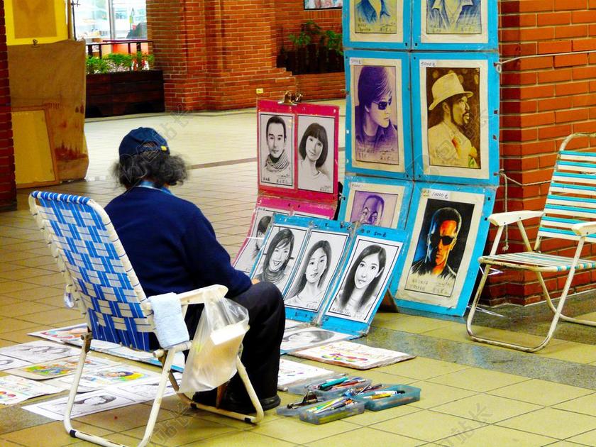 街头油画摊前老人休闲端坐油画创作背景图片