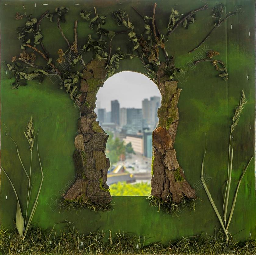 绿色城市创意孔后的城市背景图片