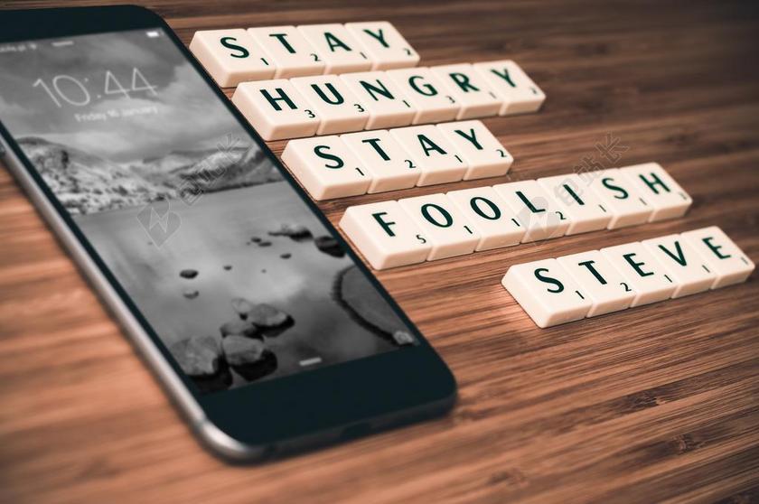 史蒂夫 · 乔布斯字母排版旁亮屏黑色苹果手机背景图片