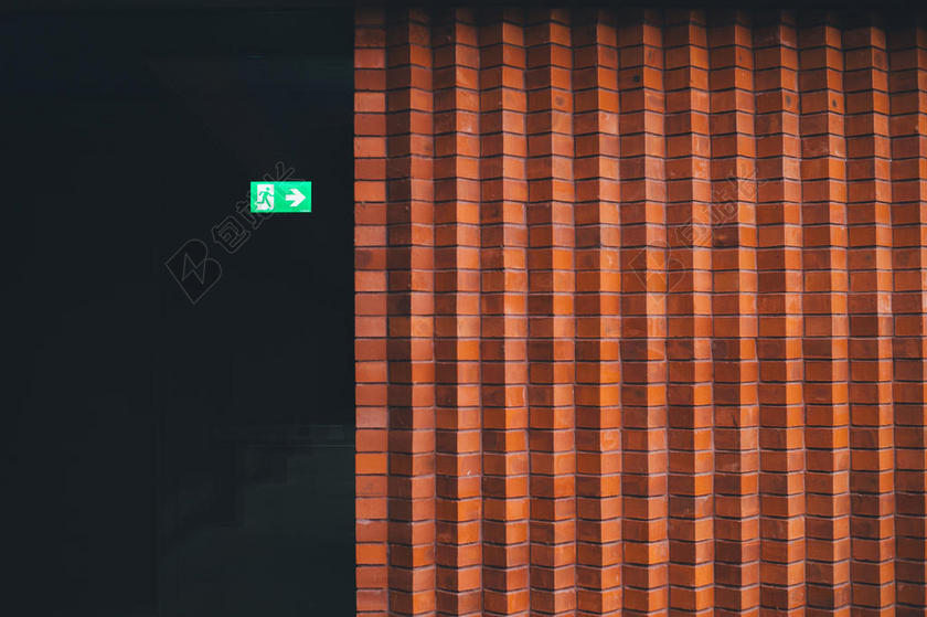 绿色的出口指示牌和黄色的砖墙背景图片