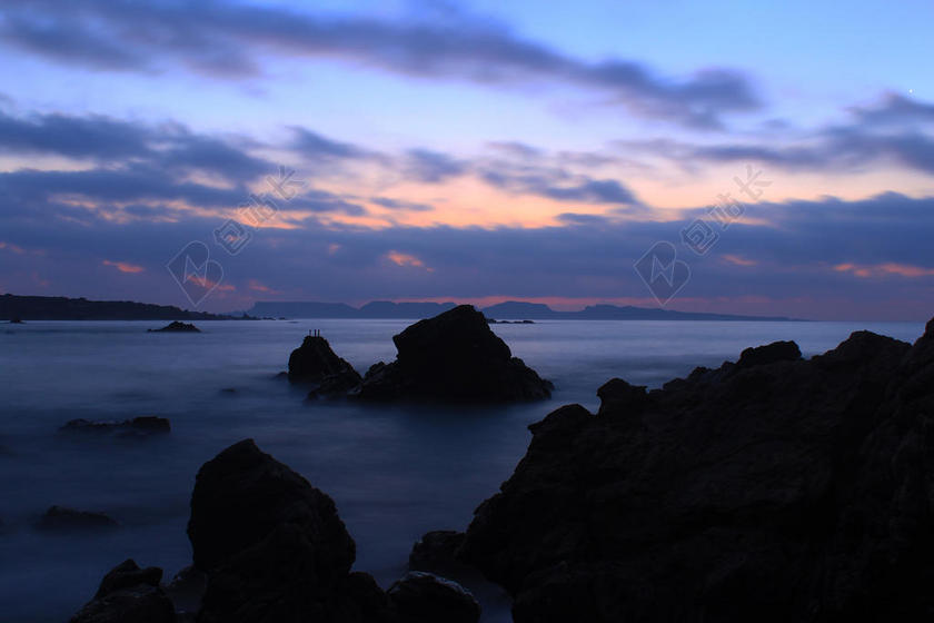 傍晚的白色海浪和黑色岩石背景图片