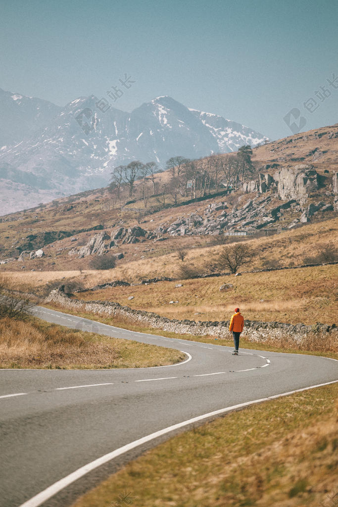 黄灰自然野人一人站在群山之下的公路上旅游群山自然背景图片