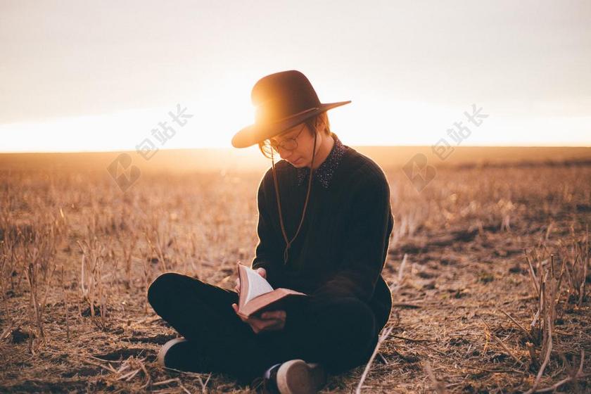 草原上看书的黑衣男人背景图片