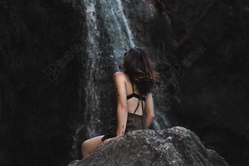 岩石上的黑发女人背景图片