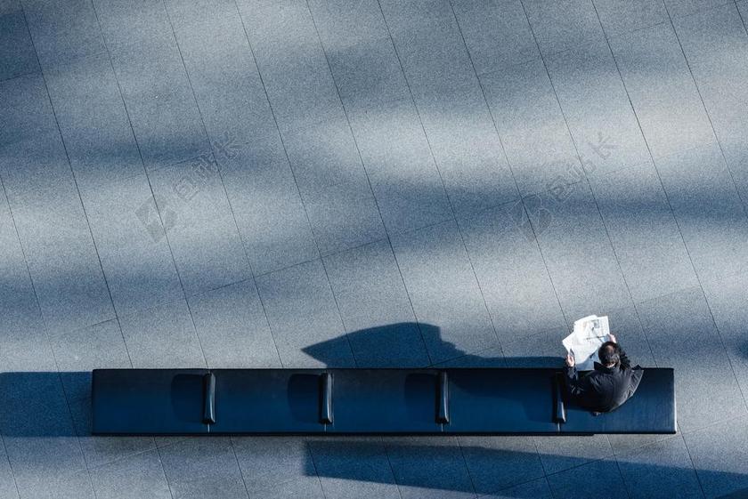 蓝白色清新人在长椅上看报背景图片