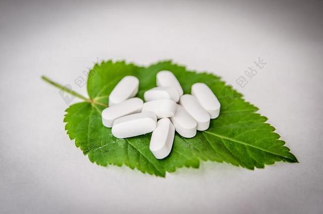 白色医疗纹理白色药丸和绿叶背景图片