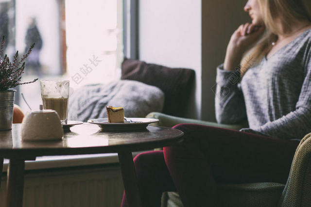 人物模糊坐沙发上看窗外的少女桌上的甜点背景图片