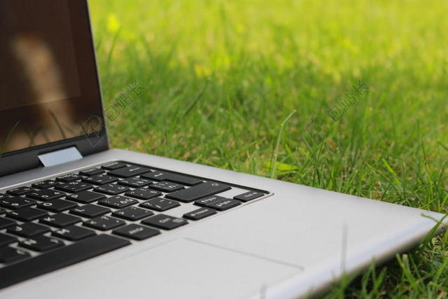 灰绿电子科技草地上放着的笔记本电脑电子产品展示背景图片