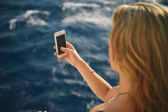 电子便捷海边拍照的女子摄影电子手机背景图片