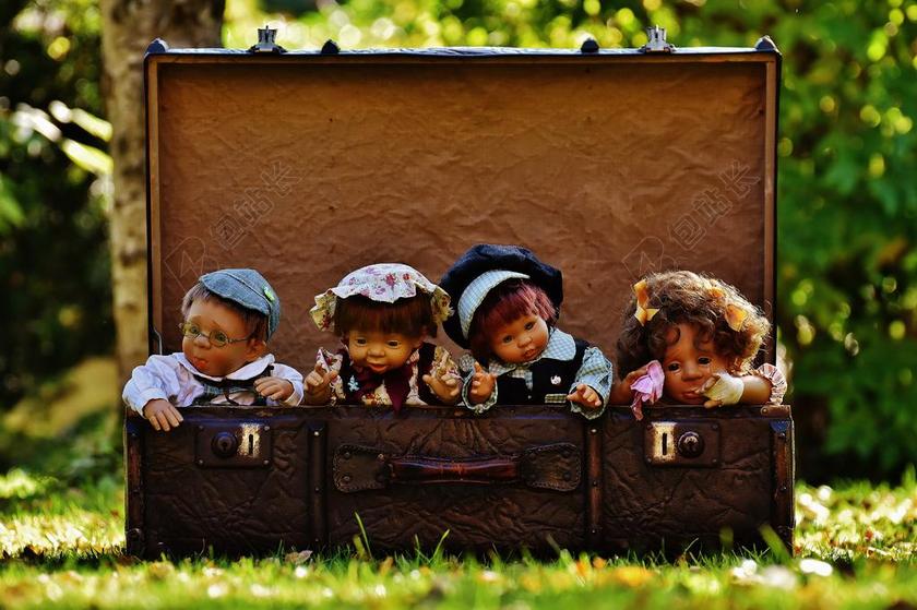 玩具可爱草地上行李箱里面的四个人偶玩具摆拍摄影背景图片