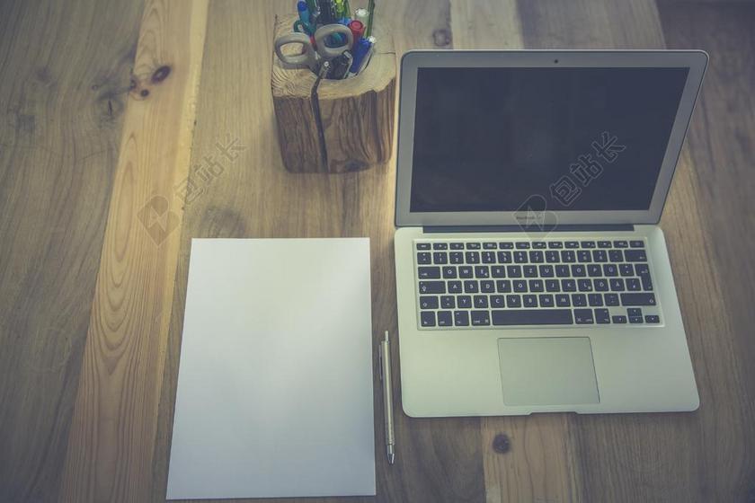 文具桌子上的白纸和电脑和笔筒背景图片