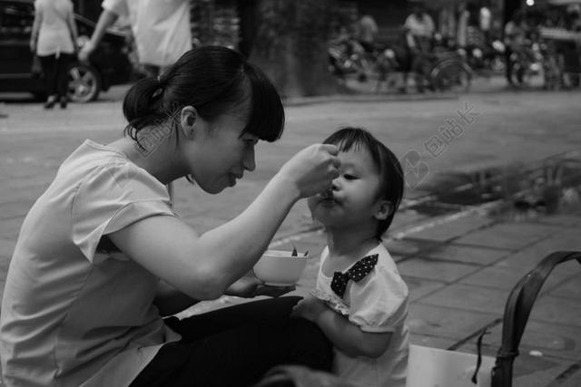 灰黑人群温馨大人正在给小孩子喂食亲子亲情人物街拍背景图片