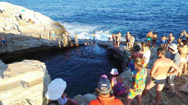 人群热闹大海边岩石上的人们旅游休闲人群背景图片