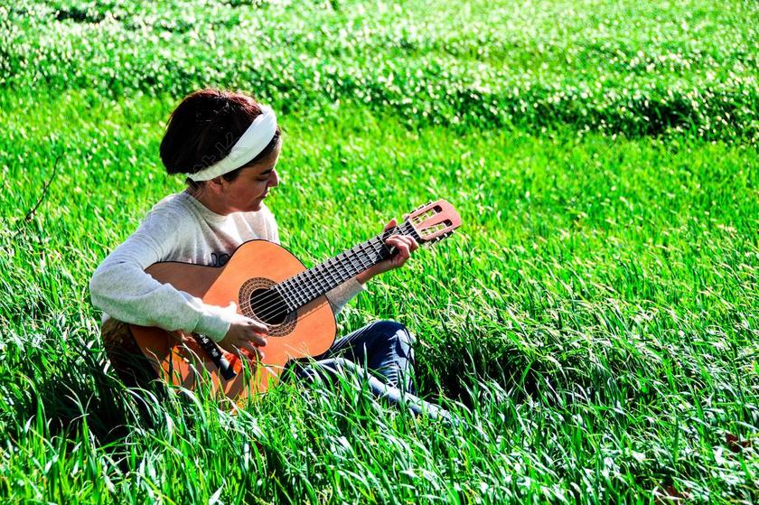 人肖像绿地上弹吉他的美女背景图片