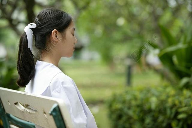 人休闲坐在公园长椅上的女孩背景图片