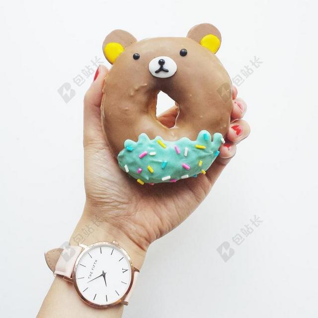 食物可爱手上拿着一个甜甜圈甜食美食背景图片