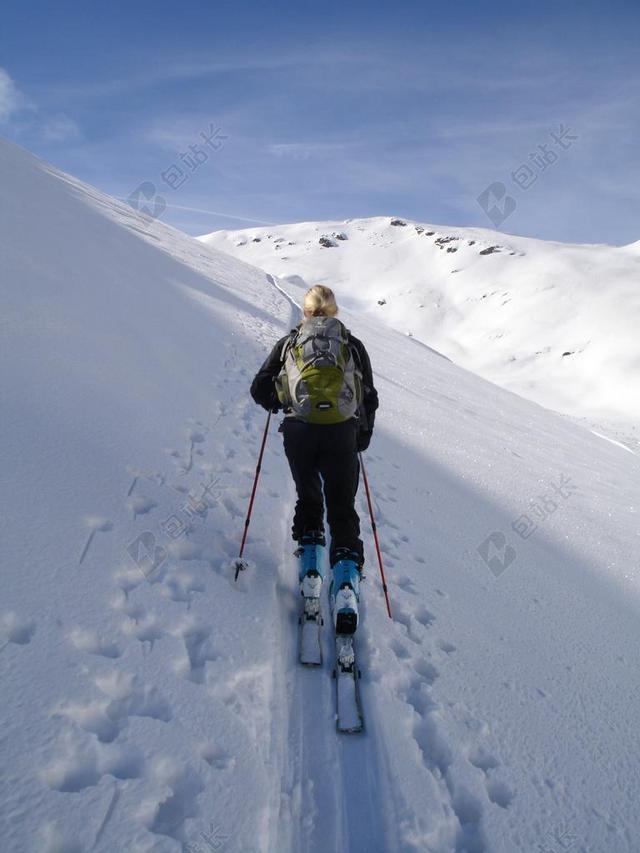 人背影雪地中跋涉的登山者背景图片