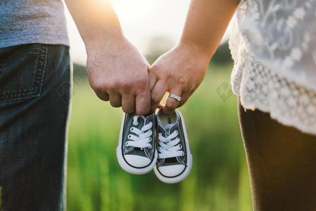 夫妇温馨牵手拿婴儿鞋背景图片