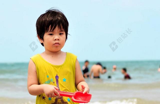 人幸福沙滩上玩沙子的男孩背景图片