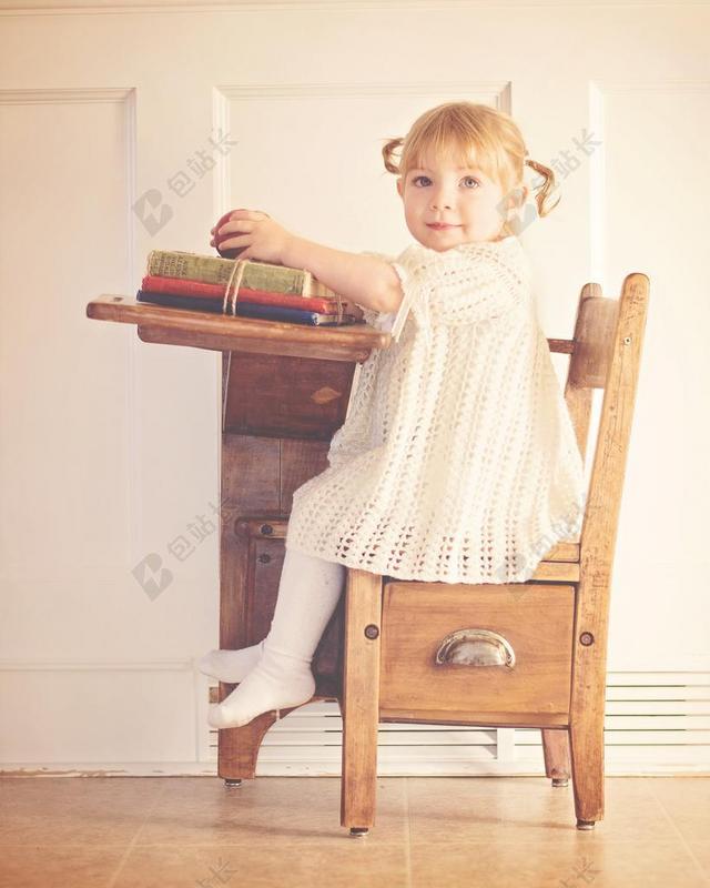 复古小女孩坐着桌子上侧面对着镜头学校幼儿园背景图片