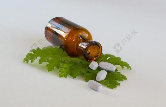 医疗绿叶上的药丸和棕色药瓶背景图片
