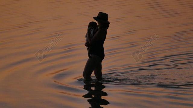 人物抱孩子过河的女人背景图片