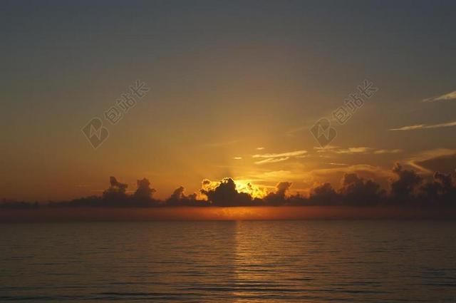 光影暖色云层间射出阳光海面落日夕阳黄昏大海背景图片