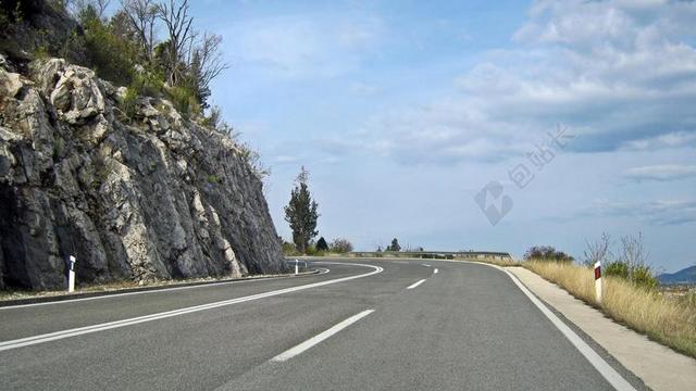蓝灰道路开阔蓝天下山边的公路道路建设背景图片