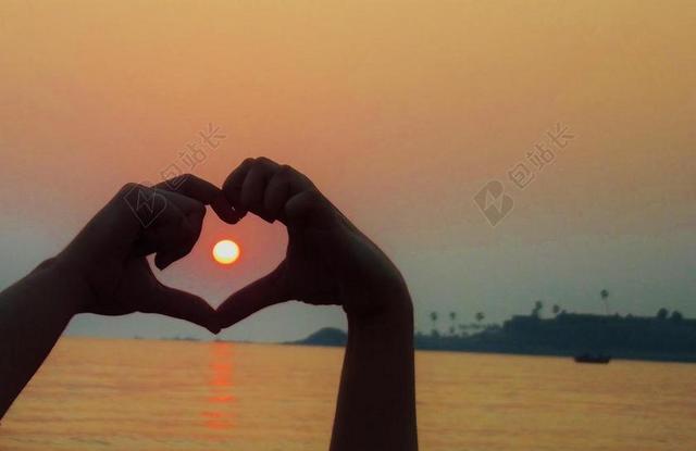 金色人浪漫心型手势中的夕阳背景图片