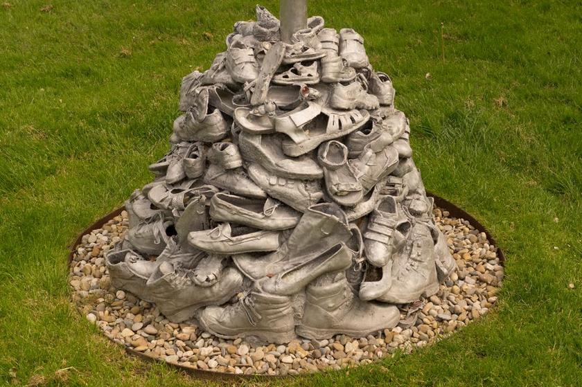 灰色雕塑旧鞋堆积草丛背景图片