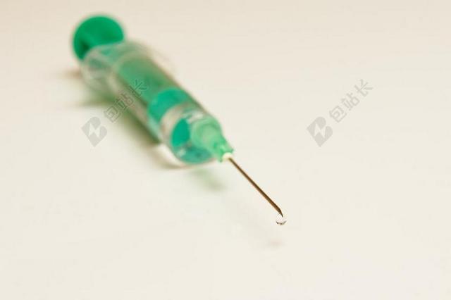 绿色的一次性注射器针头滴出一点药水背景图片