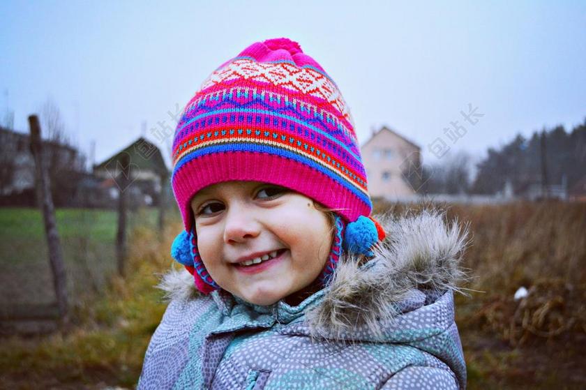爱笑的小女孩佩戴着颜色艳丽的帽子出现在秋季的田野背景图片