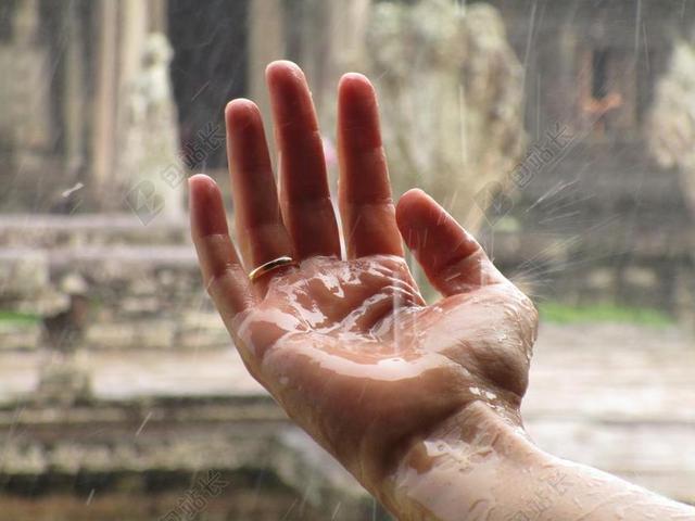 透明的小雨飞溅在佩戴代表忠贞爱情戒指的手上背景图片