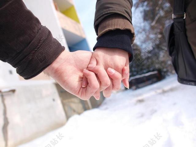 热恋情侣手牵手一起漫步走在充满积雪的冬季路上背景图片