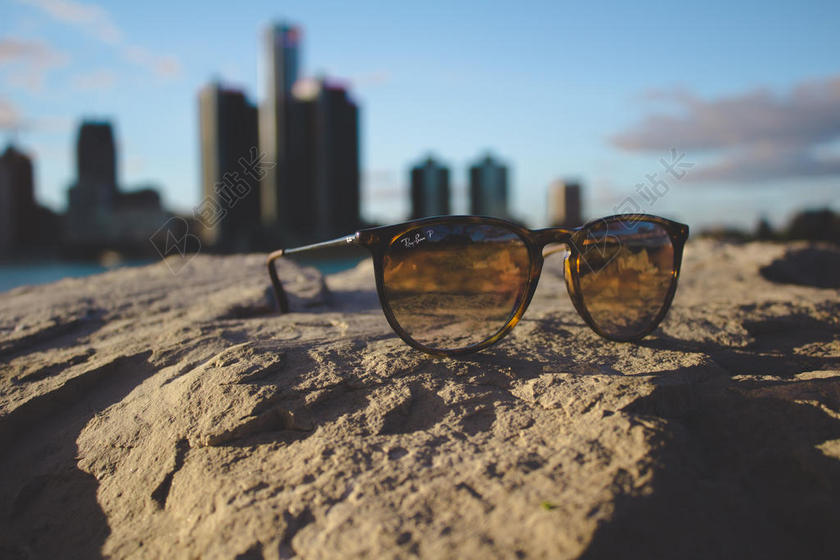摄影创意高楼背景下的沙滩上的墨镜休闲城市景观背景图片