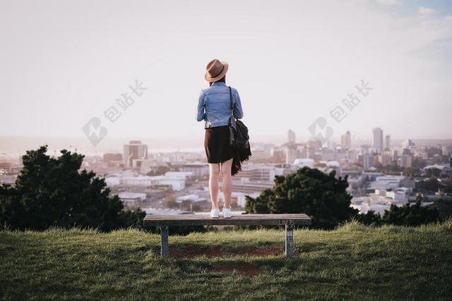 人物安静站在草地长椅上观望城市的女孩人物户外城市景观背景图片