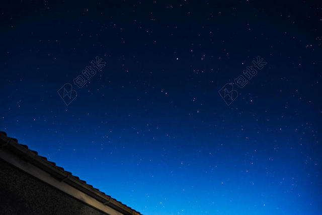 蓝色绚烂繁星闪烁下的屋檐一角星空自然夜晚背景图片