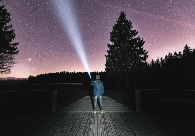 夜晚美丽的星空和拿电筒的青年背景图片