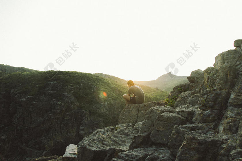 清晨的阳光和岩石上的青年背景图片
