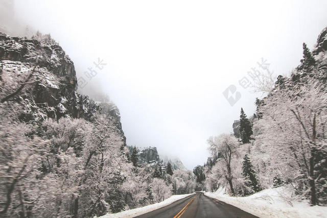 白灰道路雾气下的积雪山林公路道路建设山林雪景背景图片