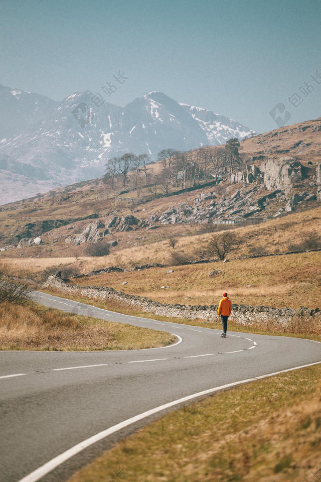 黄灰自然野人一人站在群山之下的公路上旅游群山自然背景图片