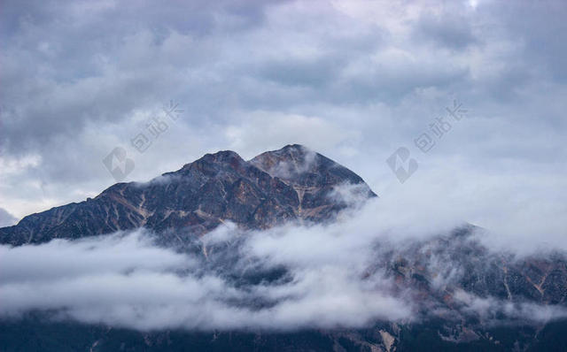 白色云雾上的灰色山峰背景图片