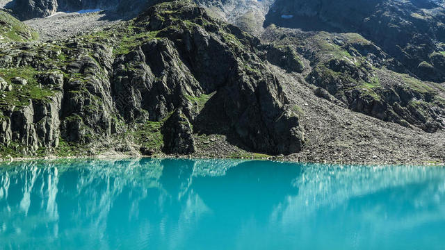 蓝色的湖水和灰色的山坡背景图片
