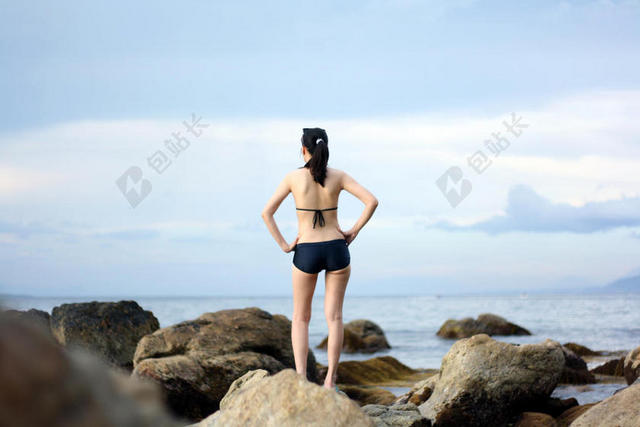 海边岩石上的比基尼美女背景图片