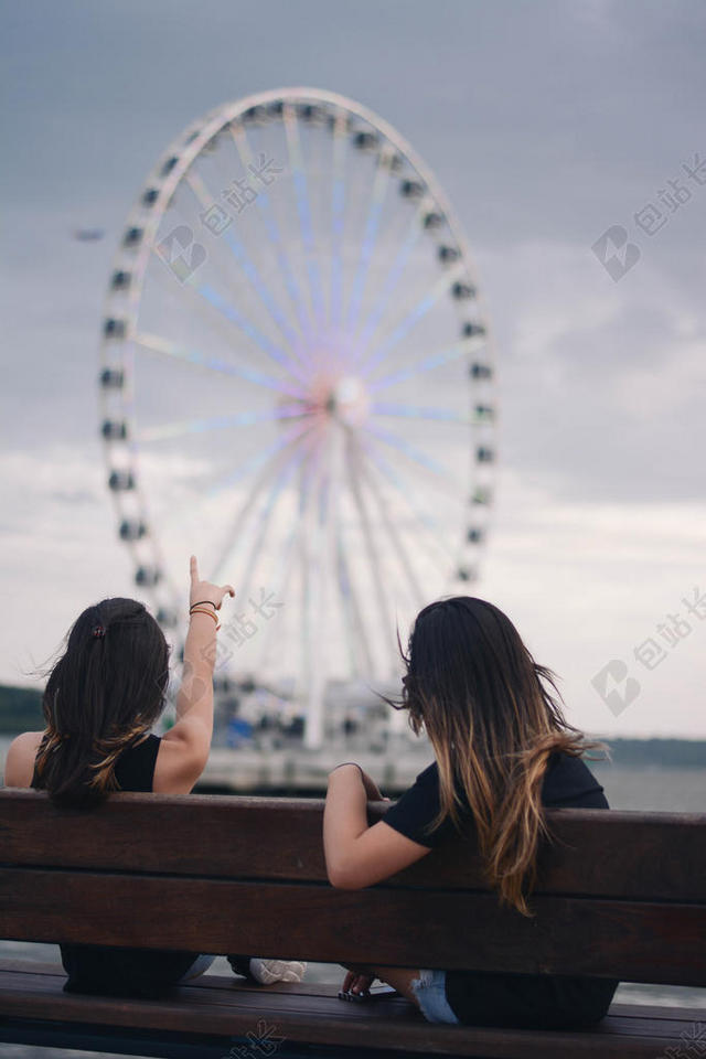 白色的摩天轮和凳子上的少女背景图片
